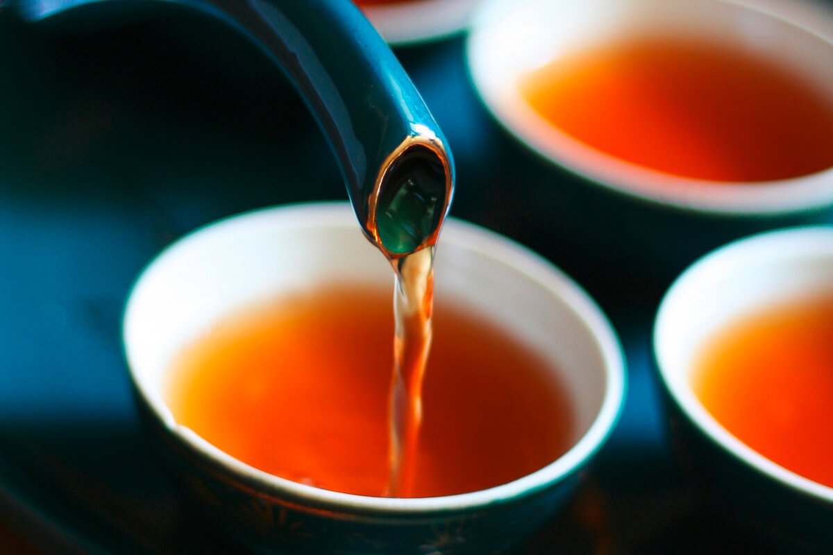 Tee wird aus einer Kanne in eine Teeschale gegossen